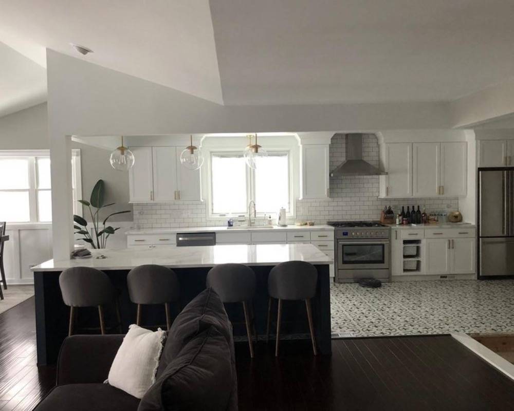 Open-plan white kitchen remodel with large island, bar seating and pendant lighting