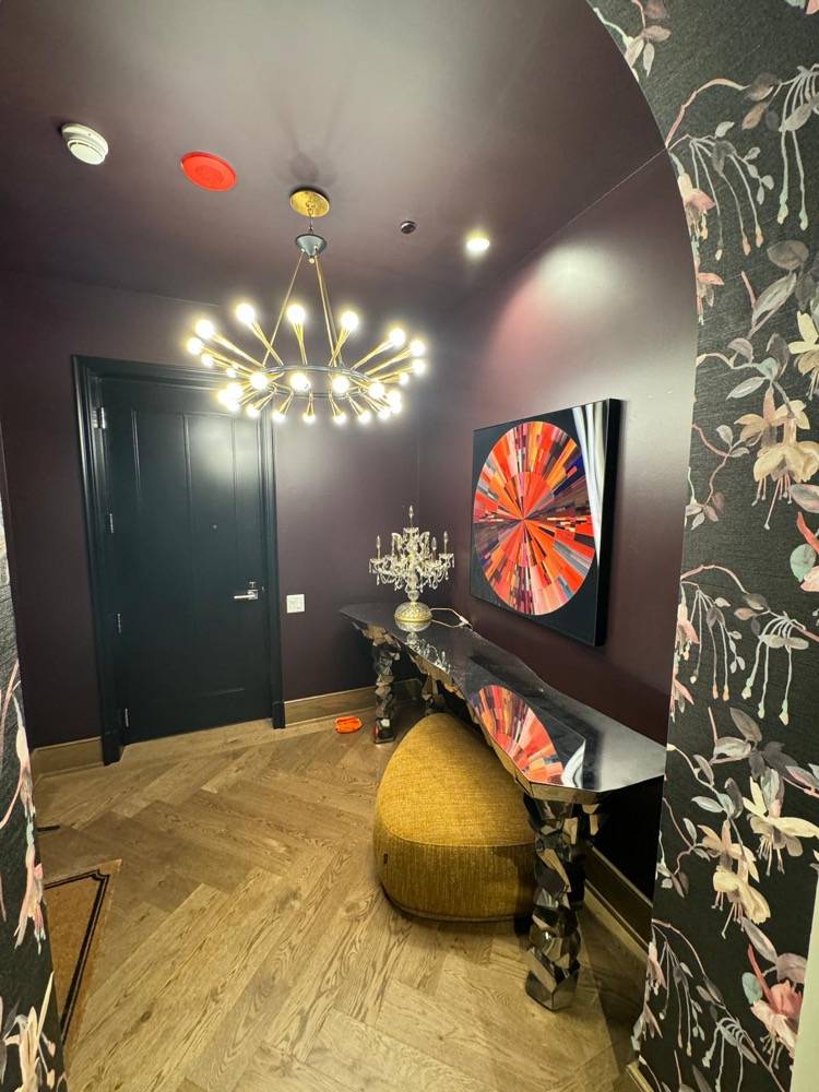 Dramatic entryway with dark walls, bold floral wallpaper and modern chandelier