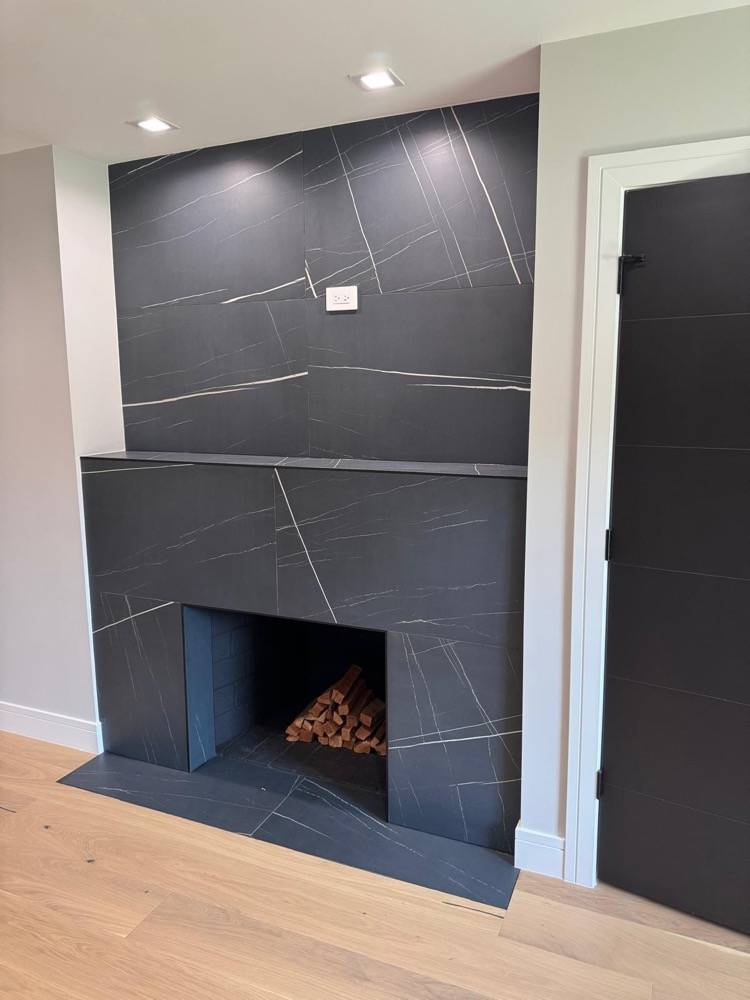 Custom dark slate fireplace surround with clean modern lines and hardwood flooring