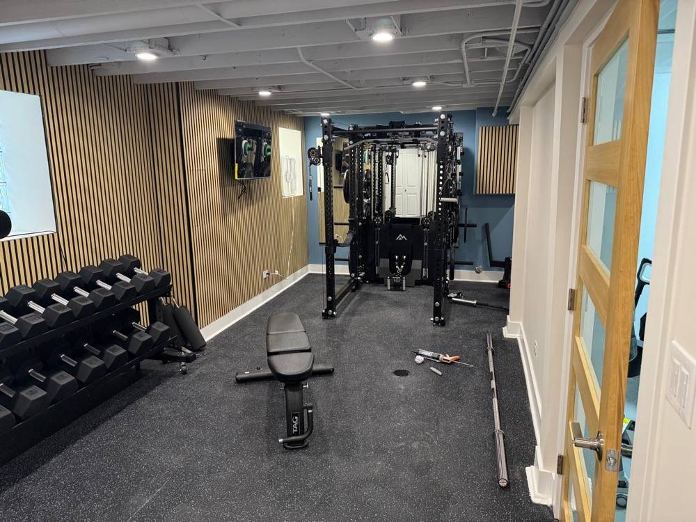 Basement gym conversion with slatted wood accent wall and professional fitness equipment