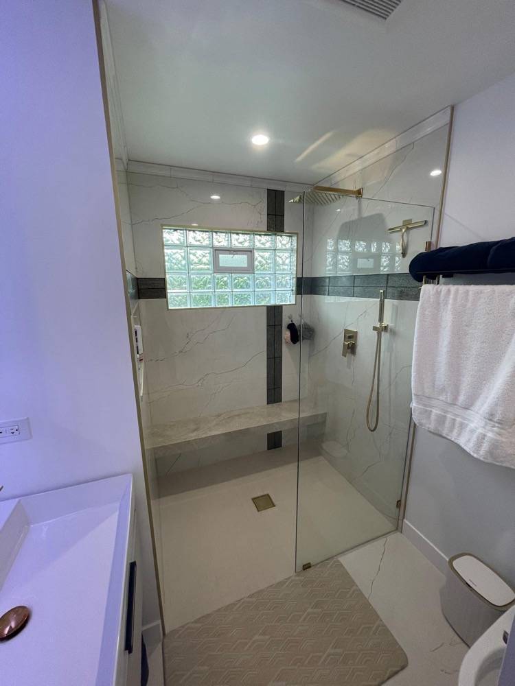 Bathroom renovation with marble-tiled walk-in shower and frameless glass door