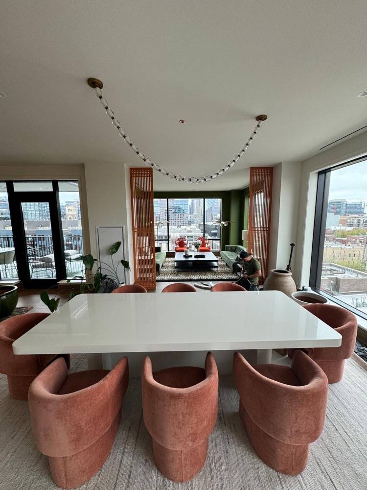 Contemporary dining room with large white table, velvet barrel chairs and city views