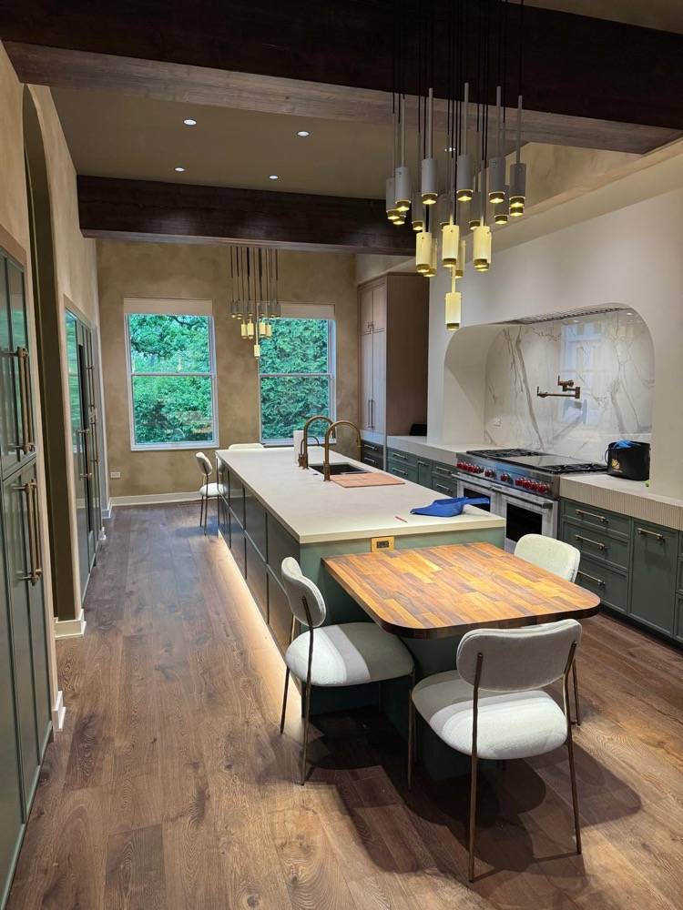High-end kitchen with sage green cabinetry, marble backsplash and cylindrical pendant lights