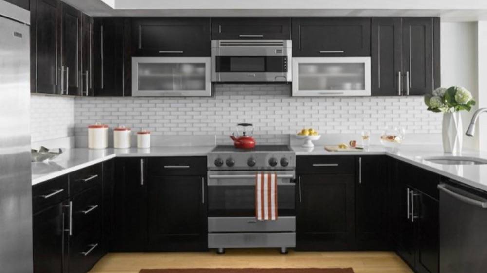 Modern kitchen with dark cabinetry, white hexagonal tile backsplash and stainless steel appliances