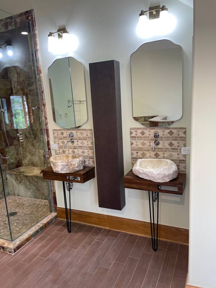 Bathroom with dual stone vessel sinks on live-edge wood counters and decorative tile backsplash