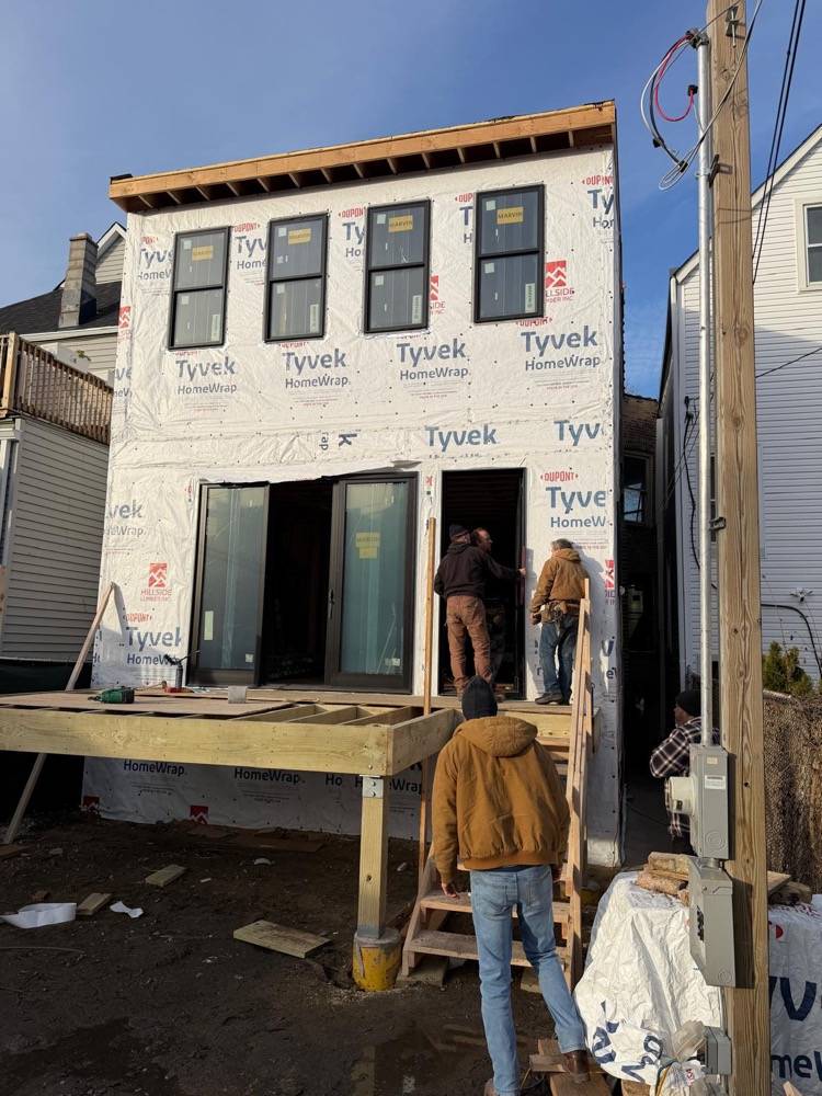 New build exterior with Tyvek house wrap, window installation and crew on site