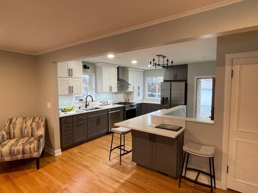 Two-tone kitchen remodel with gray and white cabinetry and quartz countertop peninsula