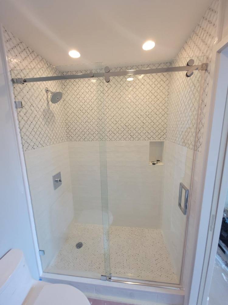 Walk-in shower with decorative arabesque tile pattern and frameless glass sliding door