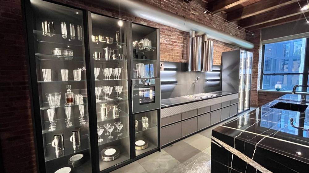 Industrial kitchen with glass display cabinets, exposed brick wall and dark marble island
