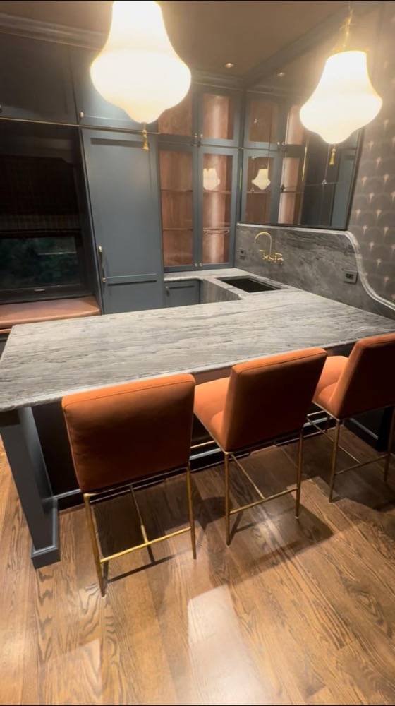 Modern bar area with stone countertop, velvet bar stools and built-in cabinetry