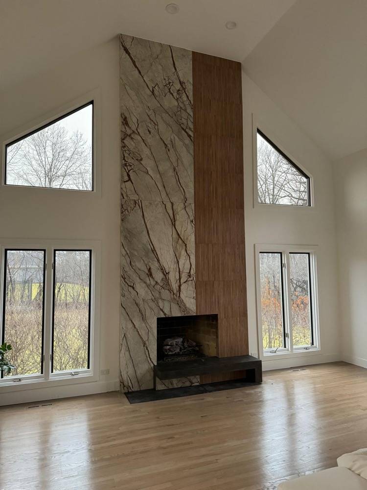 Floor-to-ceiling marble fireplace with walnut accent panel in vaulted living room