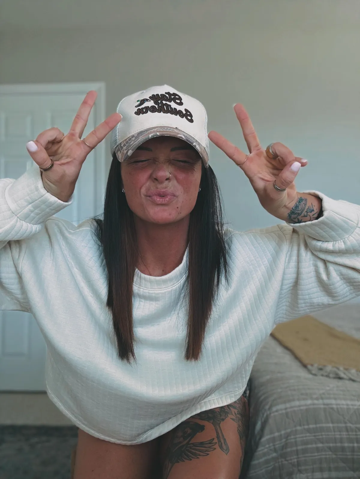 Girl with hat on holding up 2 peace signs 