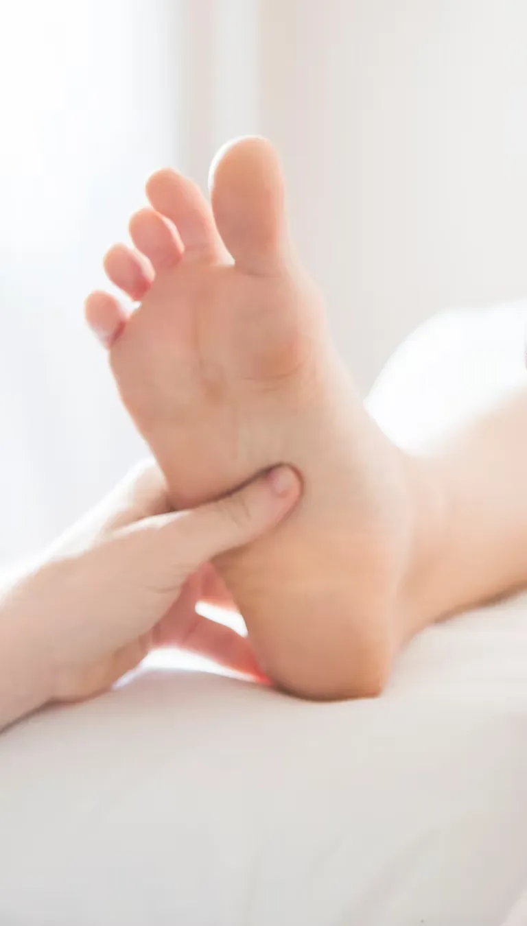 Close-up portrait of a practitioner's hands gently holding and massaging a patient's bare foot, soft natural lighting, calming and restorative mood.