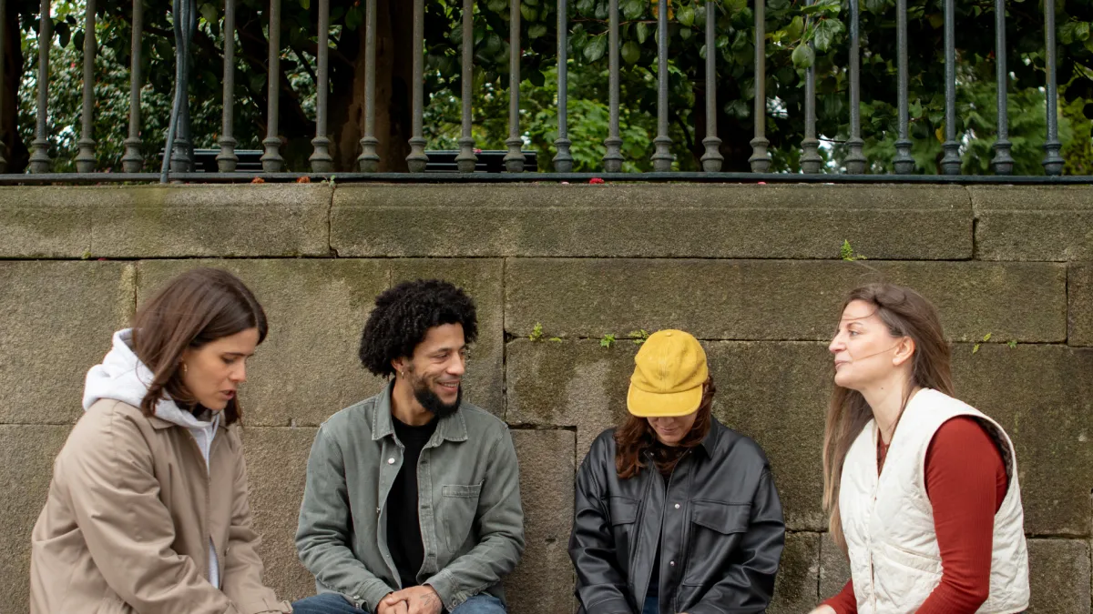 Small group gathered outdoors while one person appears quieter and less connected during the conversation.