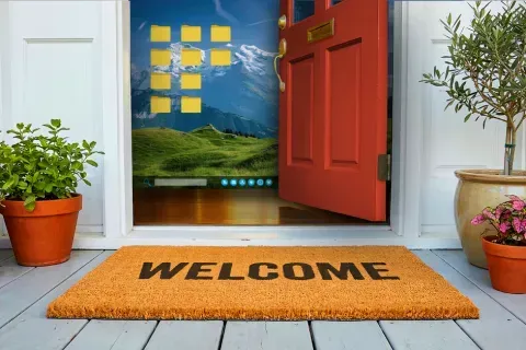 Open red door with welcome mat and potted plants revealing a desktop screen with folders and mountain wallpaper inside home.