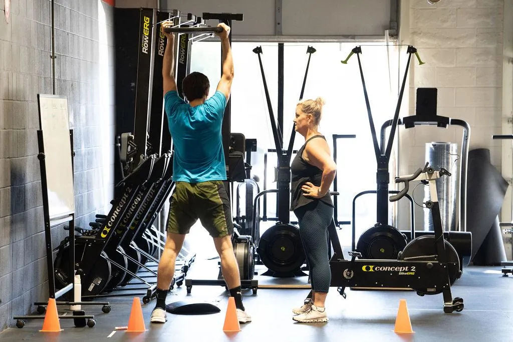 man sitting on cliffhanger looking at mountain under gloomy clouds