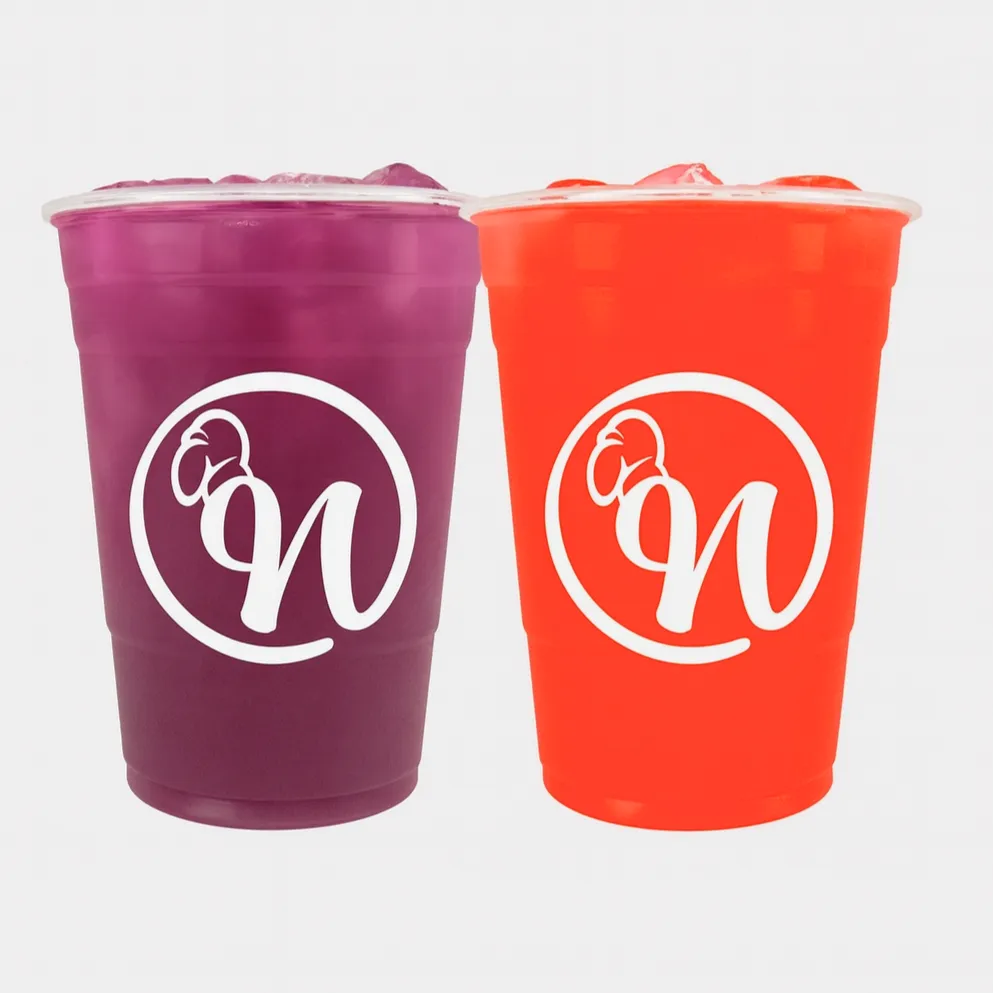 Two large plastic cups of grape and cherry Kool-Aid with ice, each featuring the white Nate’s Plates logo on the front, displayed against a clean white background.