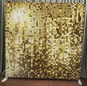 Gold sequin photo booth backdrop – shimmering metallic disc tiles in warm gold tones with sparkling light reflections, standing on floor with gray curtain behind, perfect for glamorous, wedding, corporate, or party events