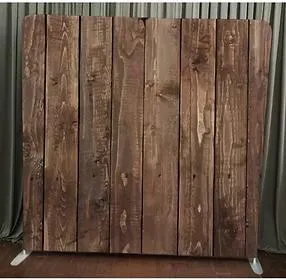 Rustic wooden plank photo booth backdrop – dark brown distressed vertical planks with natural wood grain texture, standing on floor with gray curtain backdrop behind, ideal for vintage, wedding, or rustic-themed events