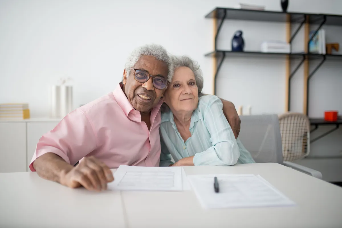 Mature couple smiling while reviewing Medicare documentation at home