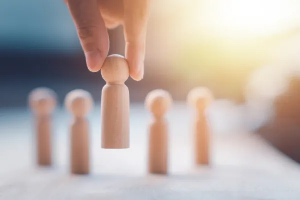 A hand selects a wooden peg from a line of others