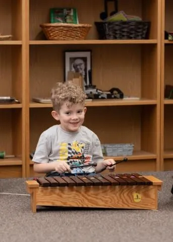 Toddler engaging in guided Montessori play with musical instruments, supporting early learning, sensory development, and self-expression at Wilkes Avenue campus