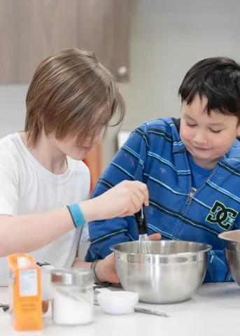 Elementary students participating in a Montessori practical life activity, working together to prepare a recipe at Wilkes Avenue campus