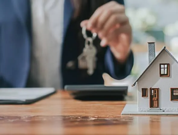 photo of keys in hand of homeowner with a small model house in frame