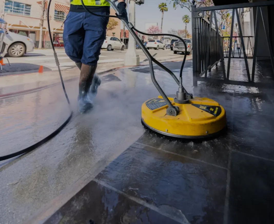 a man in a neon vest pressure washing brick/tile on the sidewalk