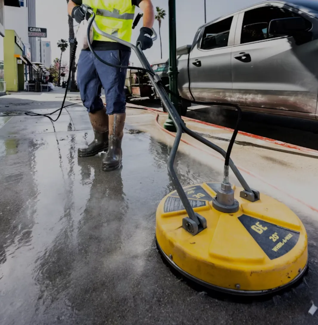 a photo of a man cleaning the street with a pressure washer