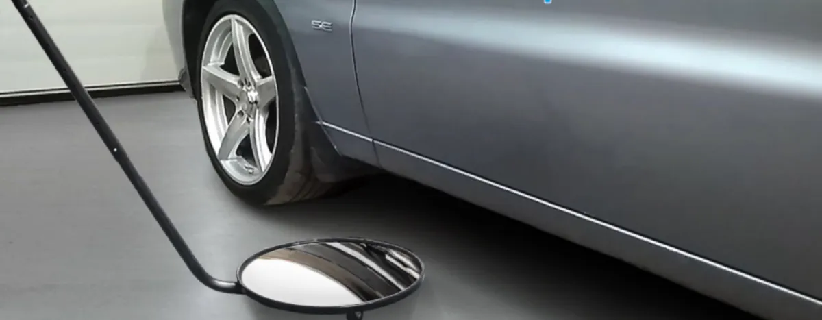 a photo of a mirror on a stick looking undernearth a vehicle