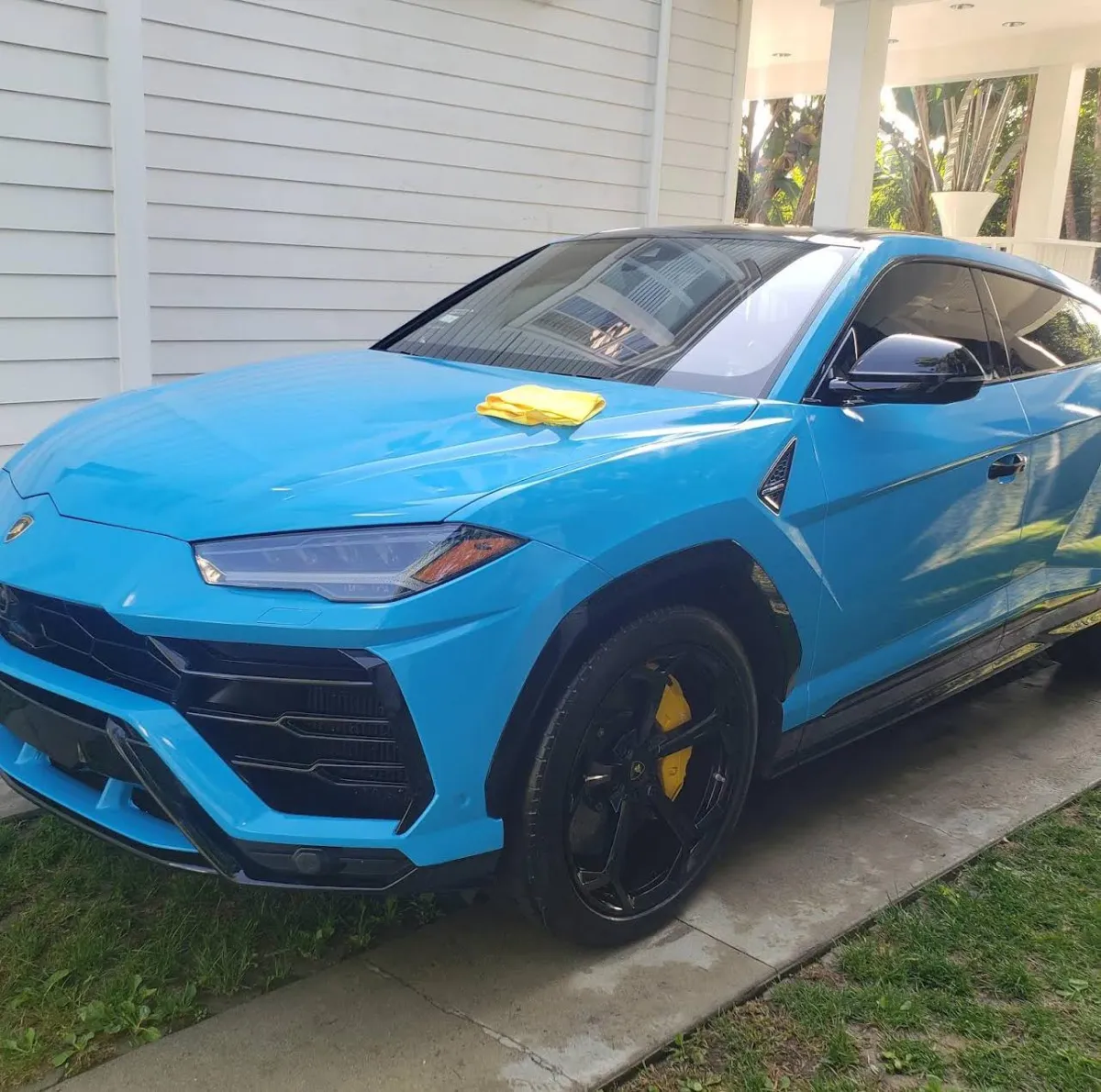 Bright blue Lamborghini Urus with yellow calipers and microfiber towel after premium mobile car detailing in Los Angeles