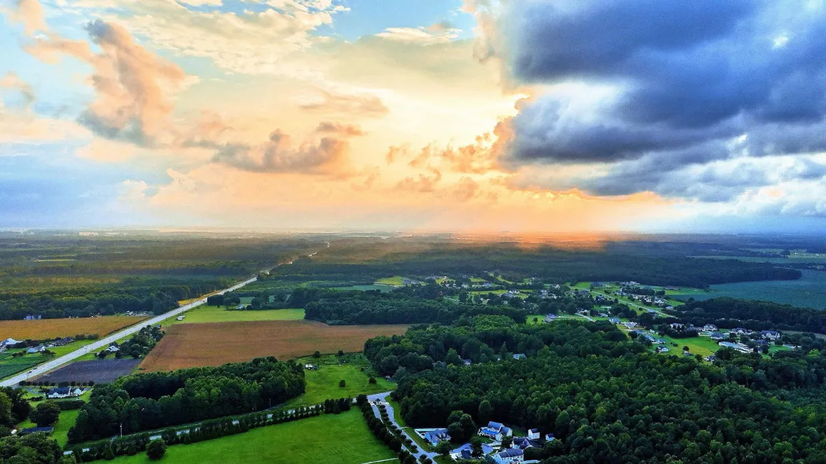 Drone shot of farmland and rural homes under dramatic skies at sunset in Georgia.