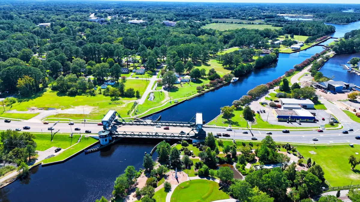 Aerial drone view of a river crossing with a bridge, roads, and surrounding green landscape in North Carolina.