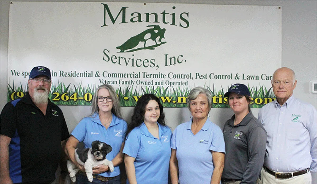 Lush green lawn in residential area with trees and landscaping, showcasing pest control services by Mantis Services, Inc.