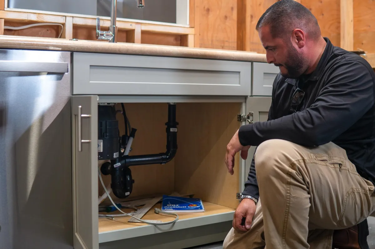 Capstone College plumbing technician instructor, Reuben, checking under the sink