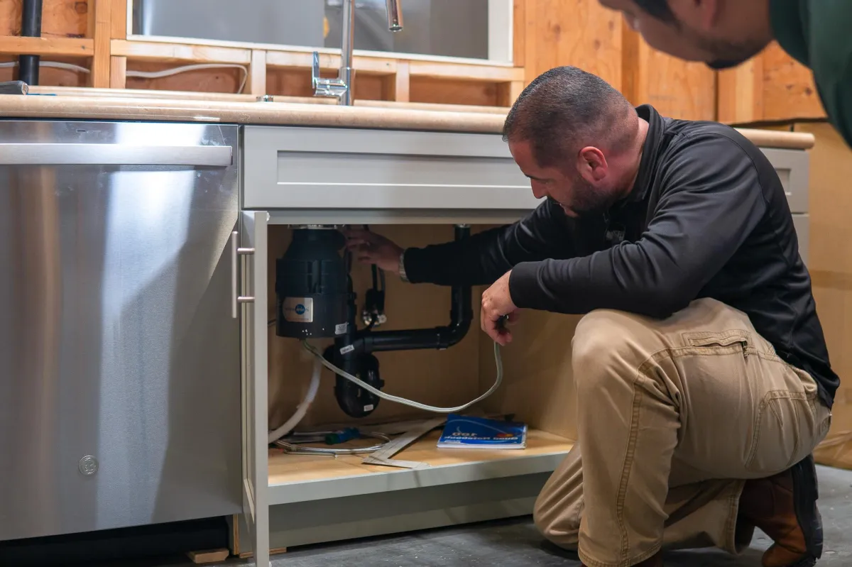 Capstone College instructor Reuben checking under the sink with a student watching