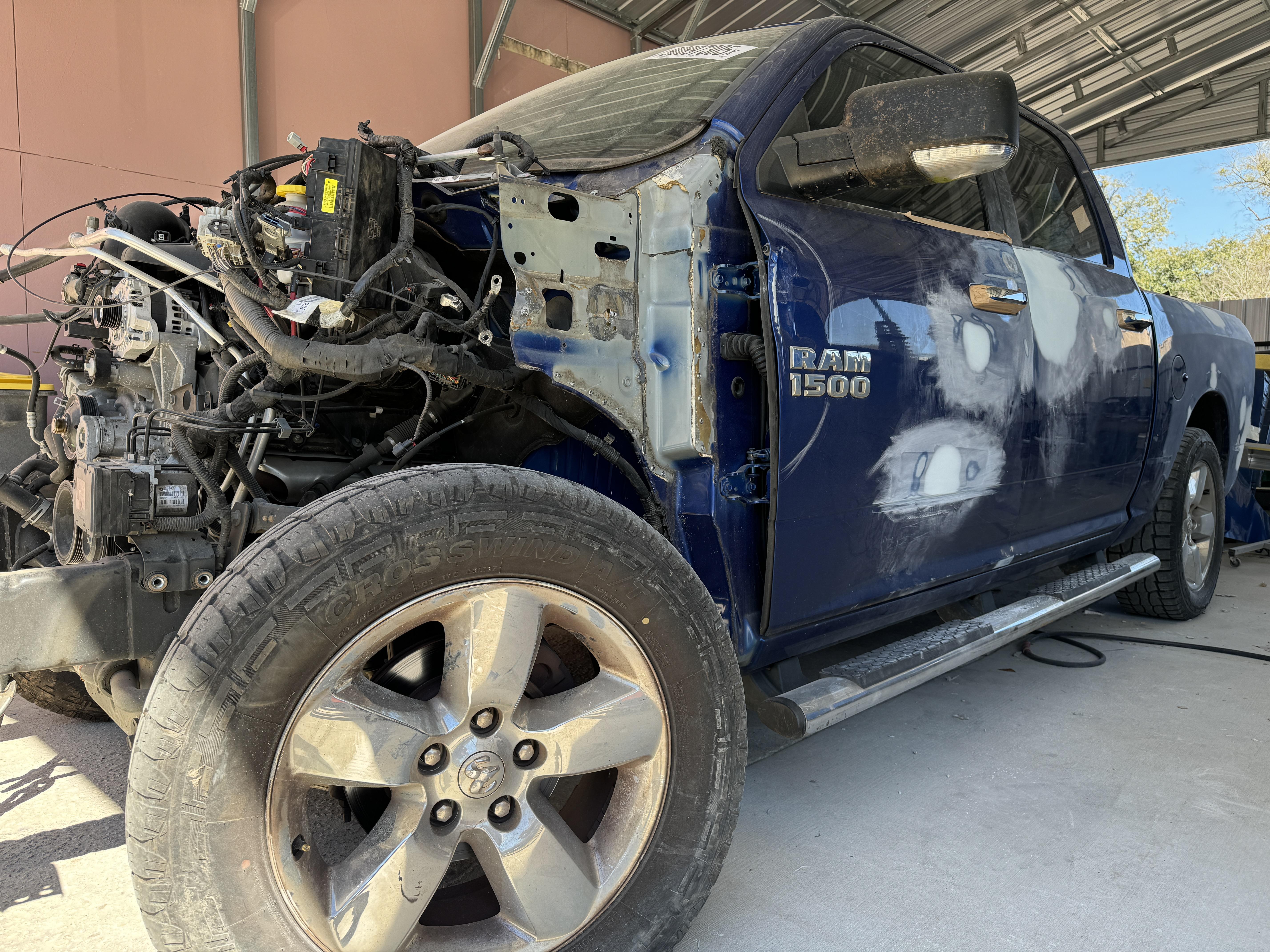 Collision repair being performed on white Mercedes on frame pulling rack at Eugene Auto Body Shop