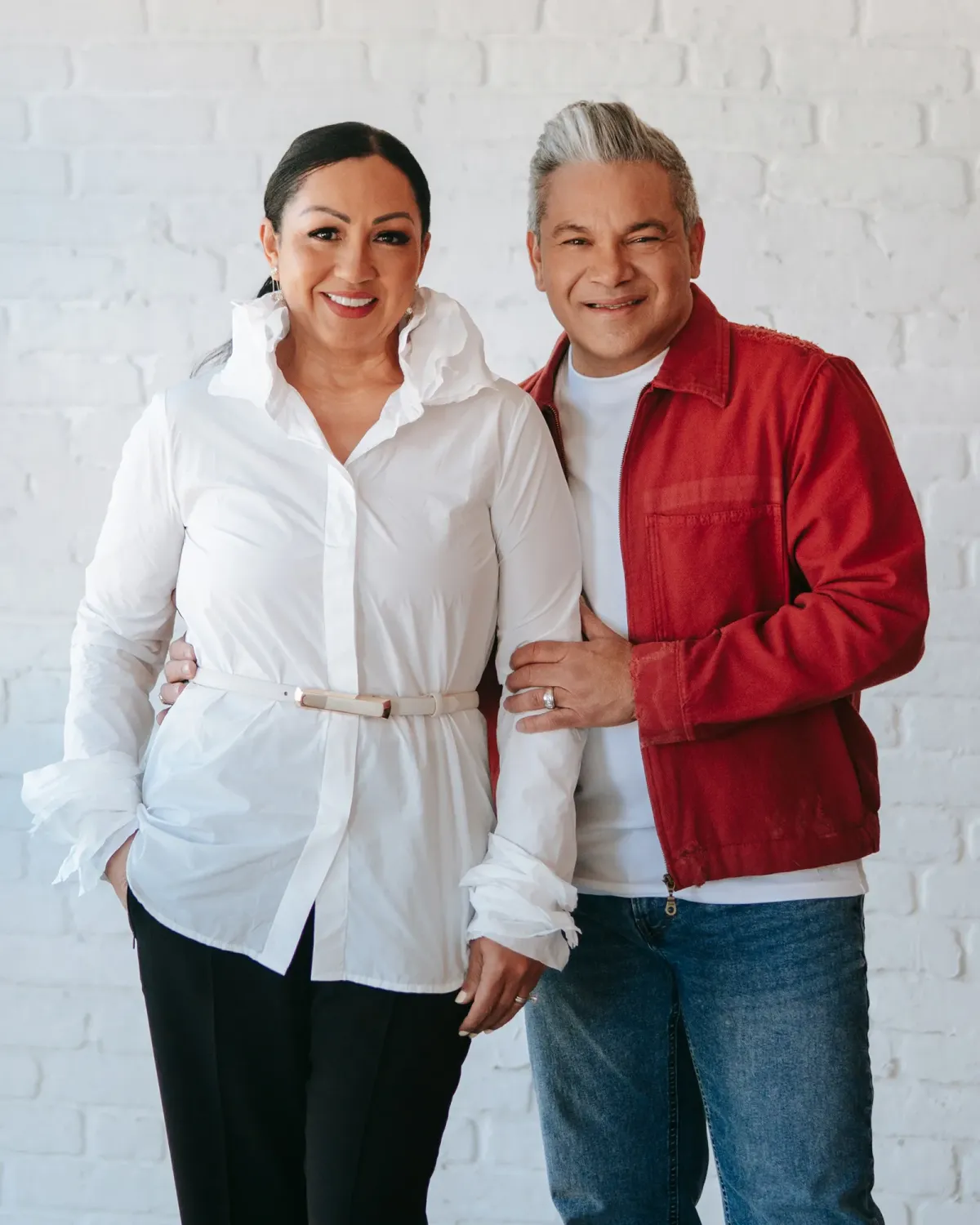 Dr. Jorge & Danisa Suárez smiling against white brick background