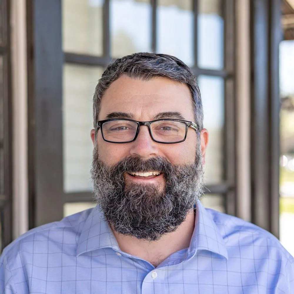 Portrait of TJ McGraw wearing glasses and smiling.