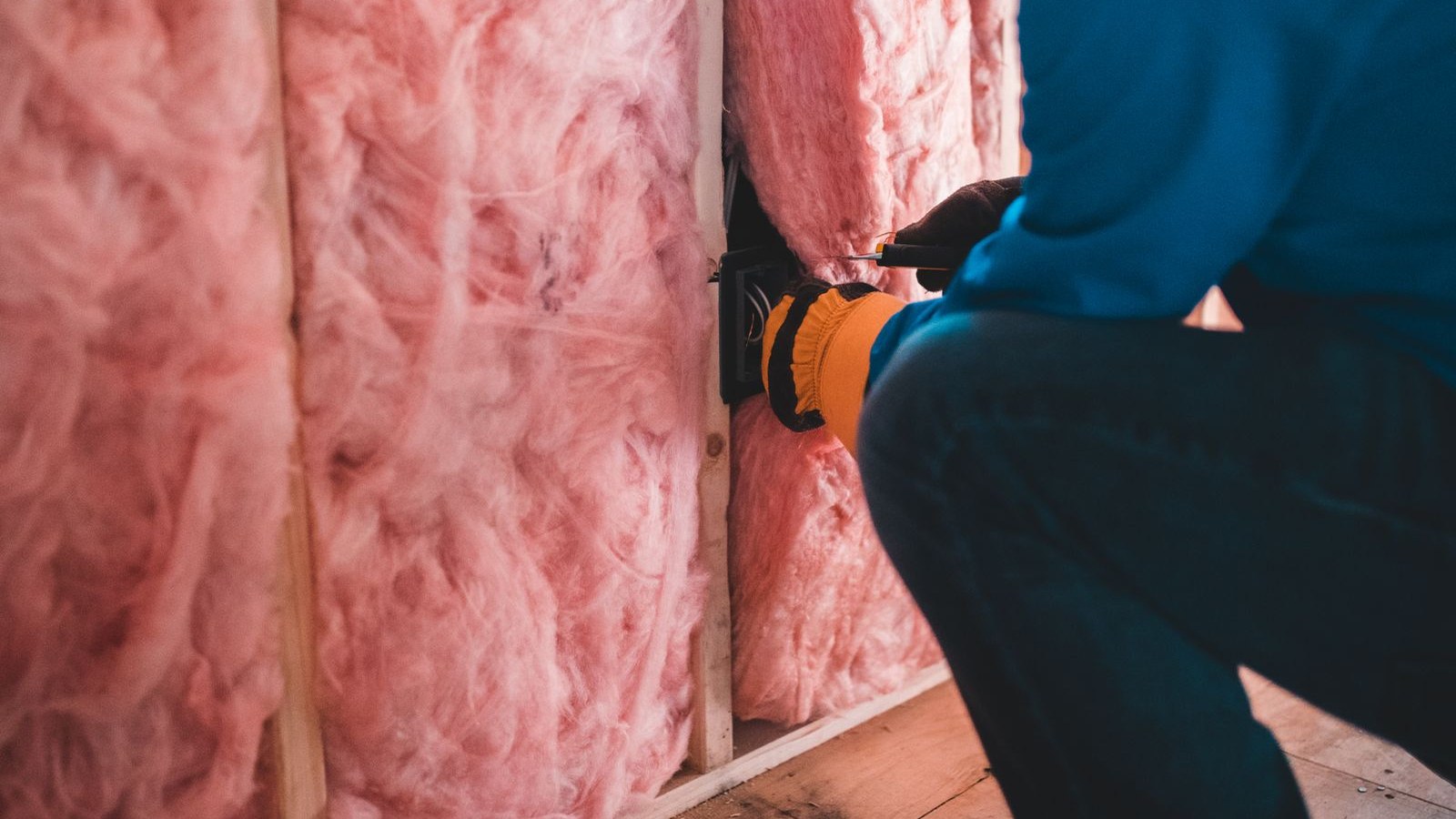 Installer fitting batt insulation into the wall cavity of a home under construction