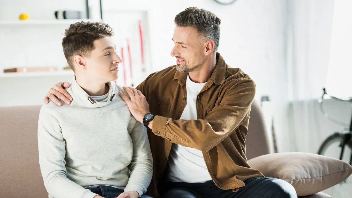 A father calmly connecting with his teenage son, demonstrating emotional safety, nervous system regulation, and the power of presence in supporting anxious children.