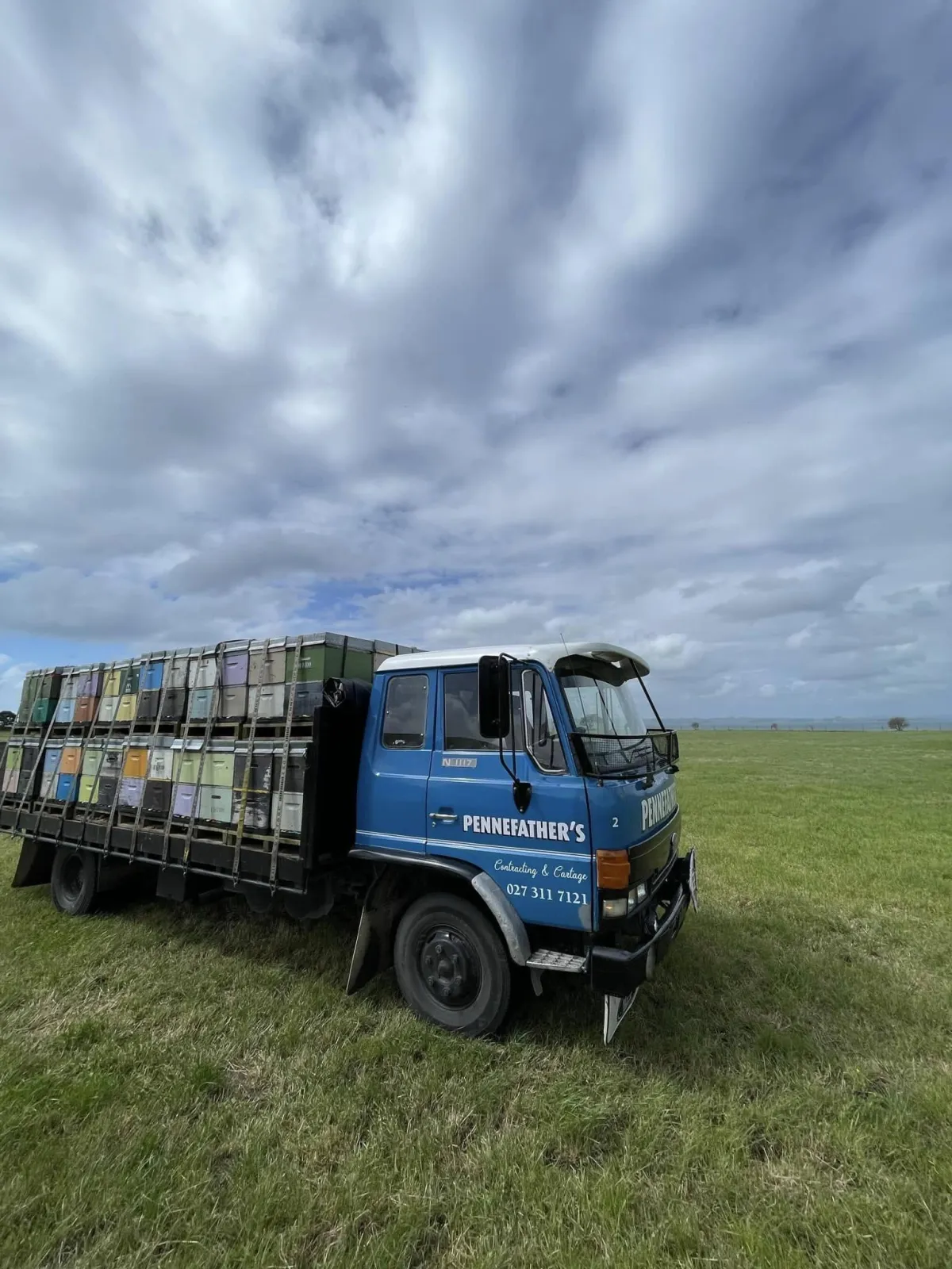 Pennefather’s truck parked in a grassy field carrying stacked beehive boxes