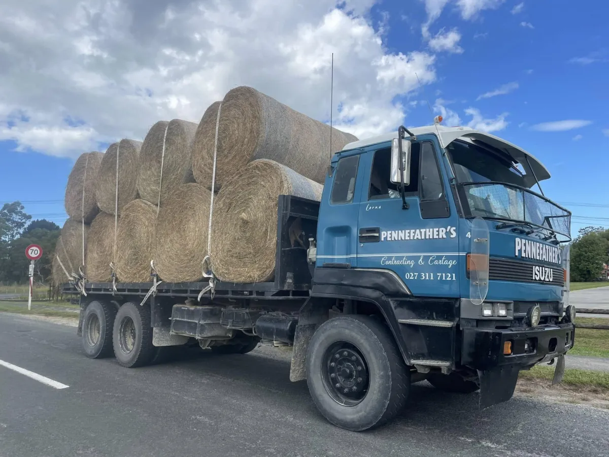 Pennefather’s truck loaded with large hay bales secured for transport on a rural road