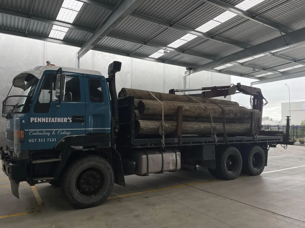 Pennefather’s truck carrying long timber logs inside a covered industrial facility