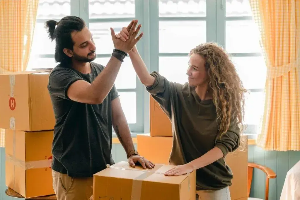 Happy couple high-fiving after packing moving boxes for their new rental home.