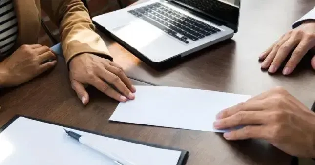 Hands exchanging a rental agreement or application form across a wooden table.