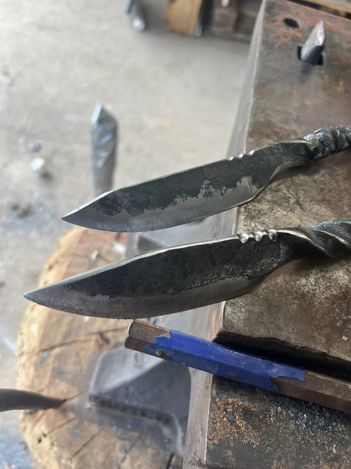 A pair of railroad spike knives on an anvil