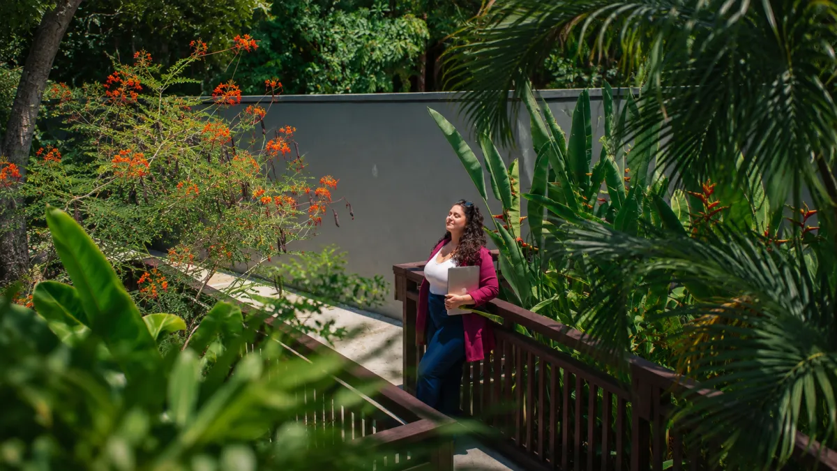 Richelle working peacefully on her laptop from a sunlit European cafe terrace overlooking coastal hills