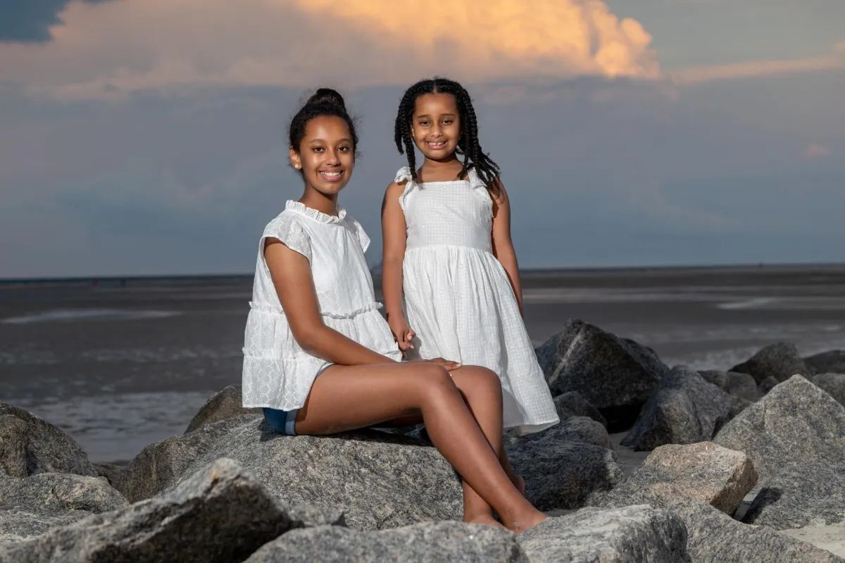 Two sisters posing together on the beach during a sunset session on Hilton Head Island, photographed by Seaside Beach Photography.